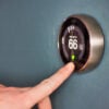 Hand,Operating,Smart,Thermostat,To,Save,Money