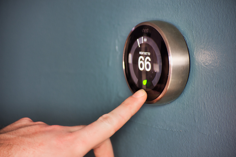 Hand,Operating,Smart,Thermostat,To,Save,Money